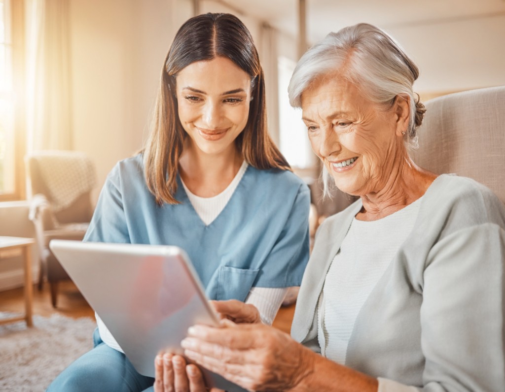 Caregiver and elderly patient using tablet together